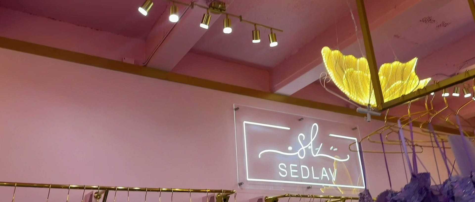 The white neon SEDLAV sign glowing on the pink salon wall