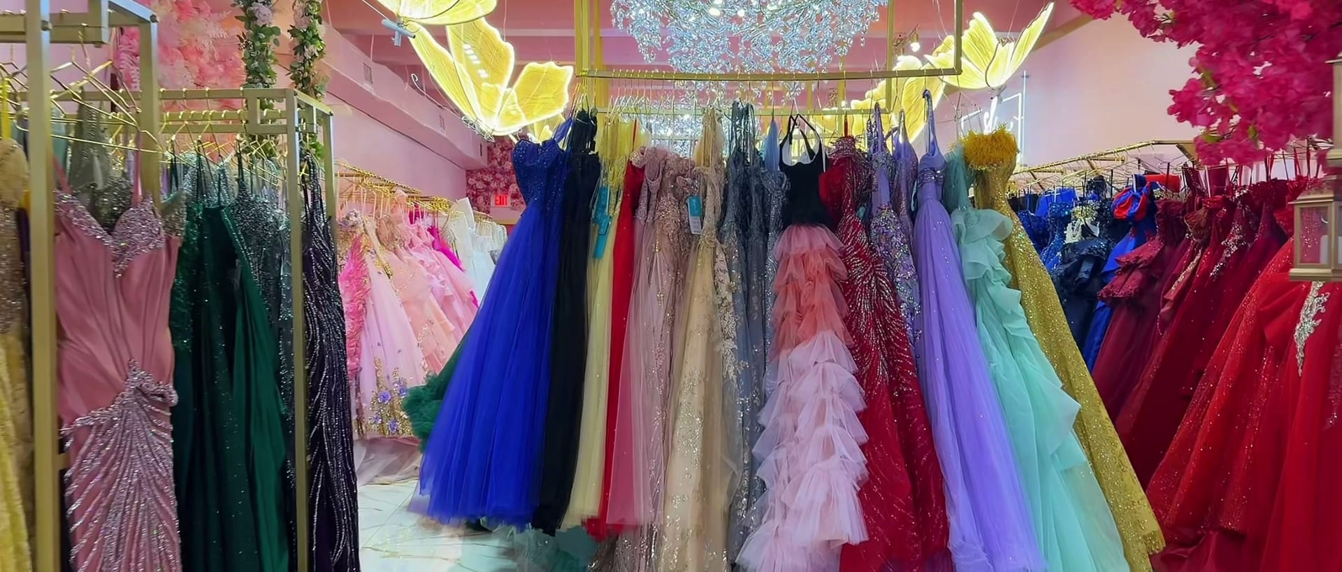 Racks of ball gowns under golden butterfly lights