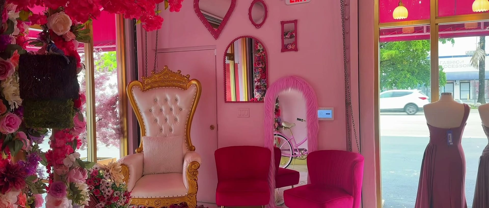 A white and gold throne chair beside a wall of roses in the salon